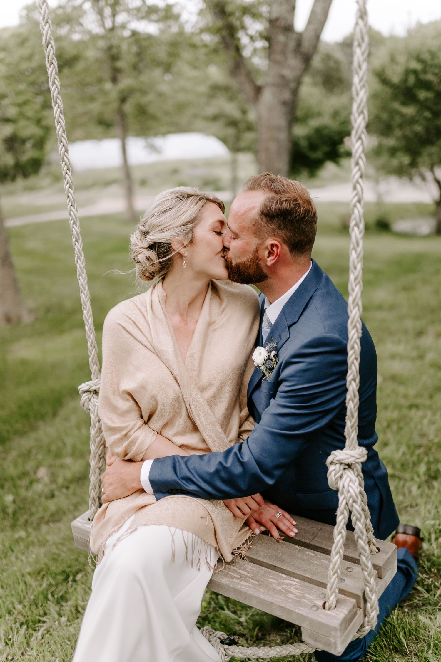 Romantic couple sharing tender moments on a rustic wooden swing outdoors.