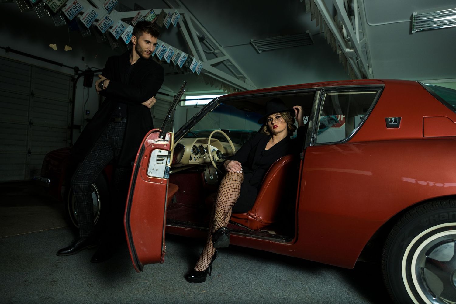 Film noir inspired scene with vintage red car in dimly lit garage.