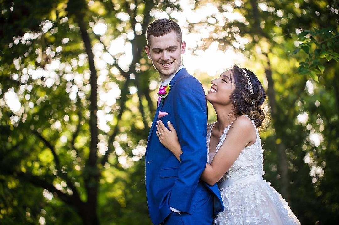 Joyful wedding portrait captured in natural garden setting.