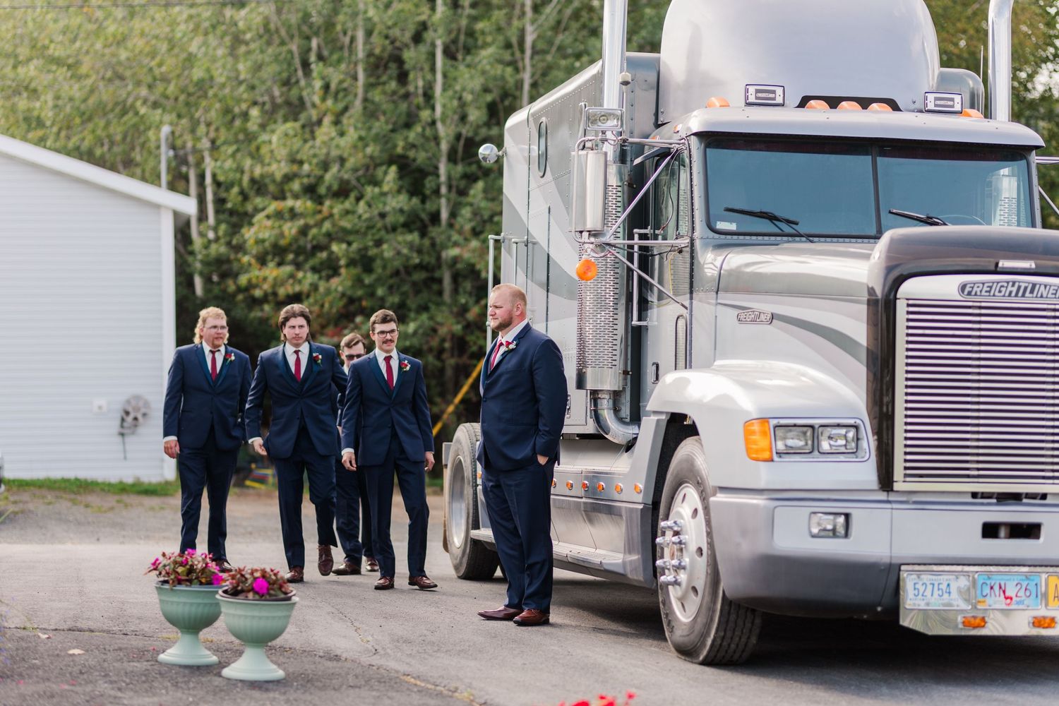 Wedding party members gather near parked semi trucks for unique outdoor photos.