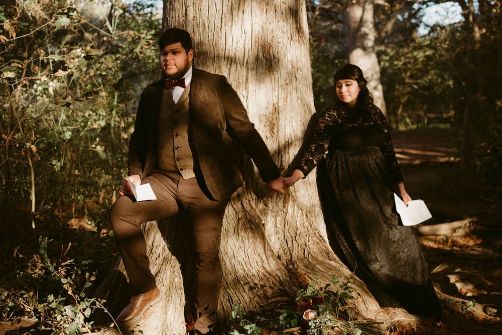 A romantic vintage photography session with a couple in period clothing holding hands by a majestic tree.