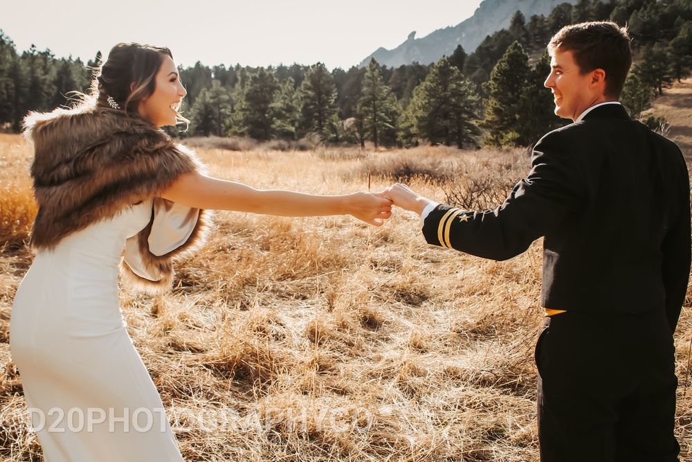 Happy couple dancing and holding hands in a sunlit mountain meadow.