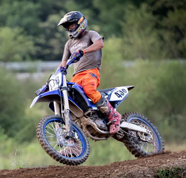 Motocross rider leaning into turn on dirt track with dynamic action shot.
