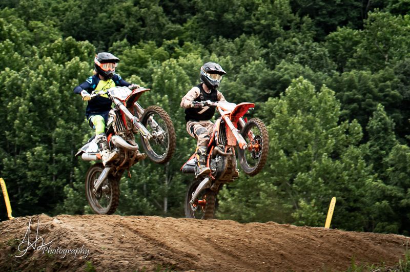 Multiple dirt bikes soaring through the air during motocross race jump sequence.