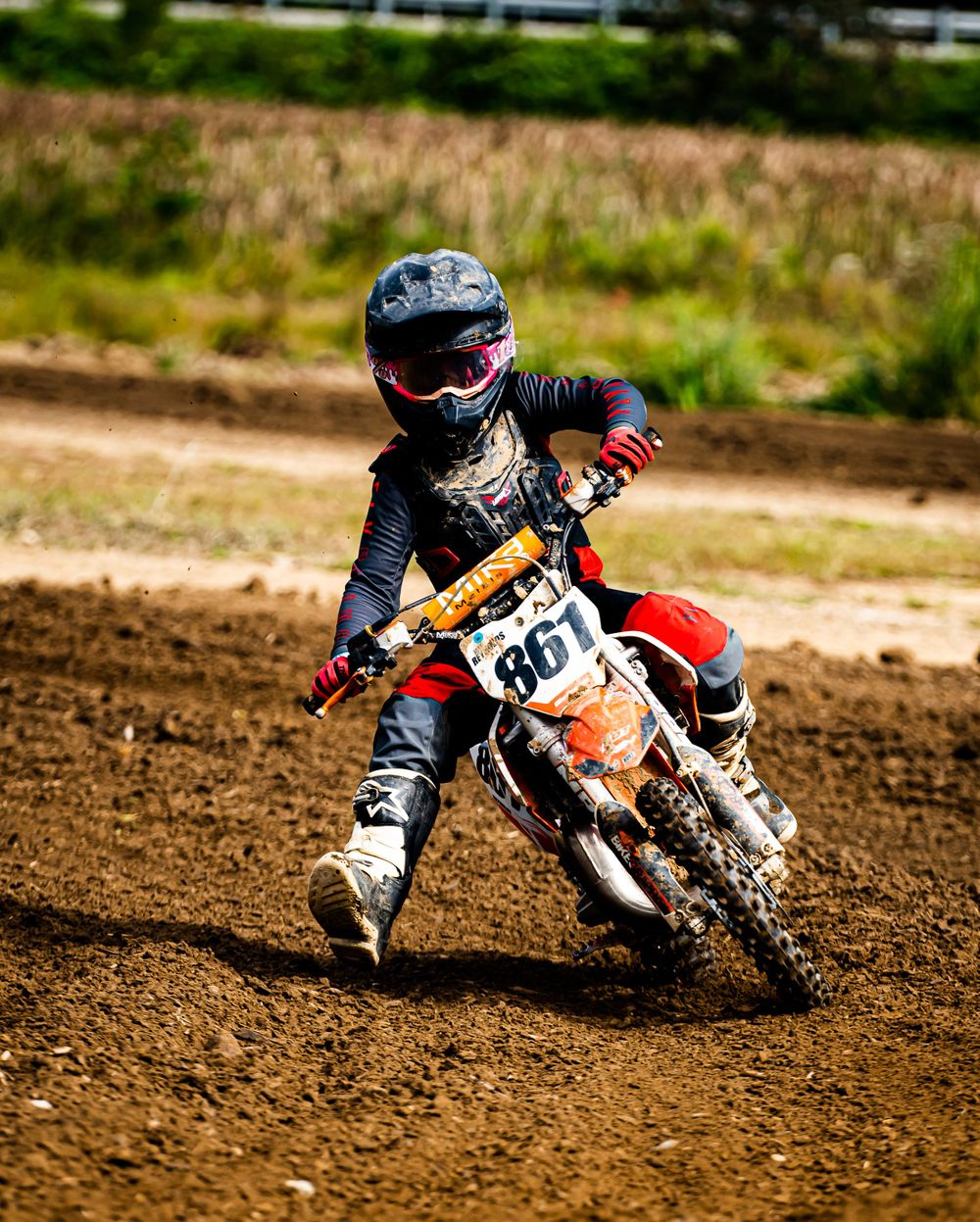 Low angle shot of motocross bikes racing through dirt track corner.