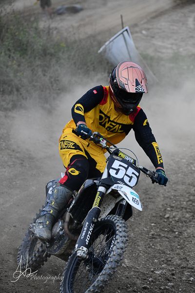 Rider in yellow jersey powers through dusty motocross track.