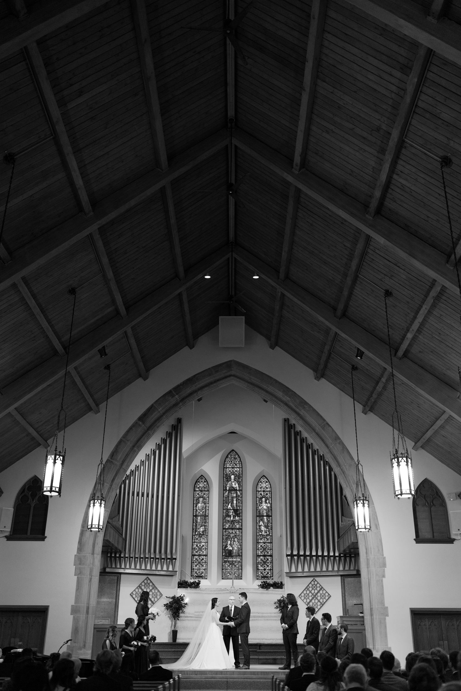 A church wedding ceremony in progress inside a gothic-style chapel with stained glass windows.