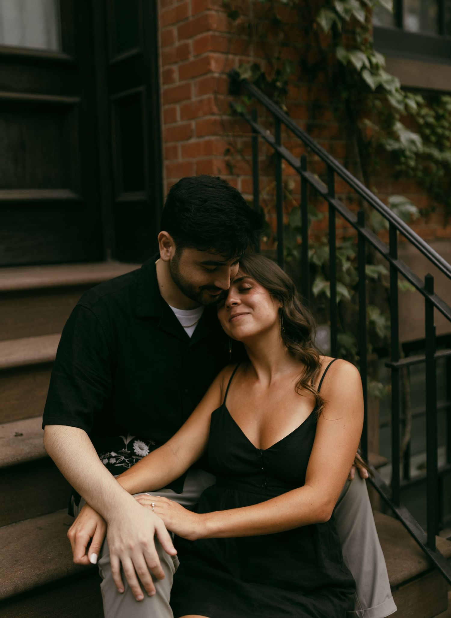 A couple shares an intimate moment on urban brick steps at dusk.