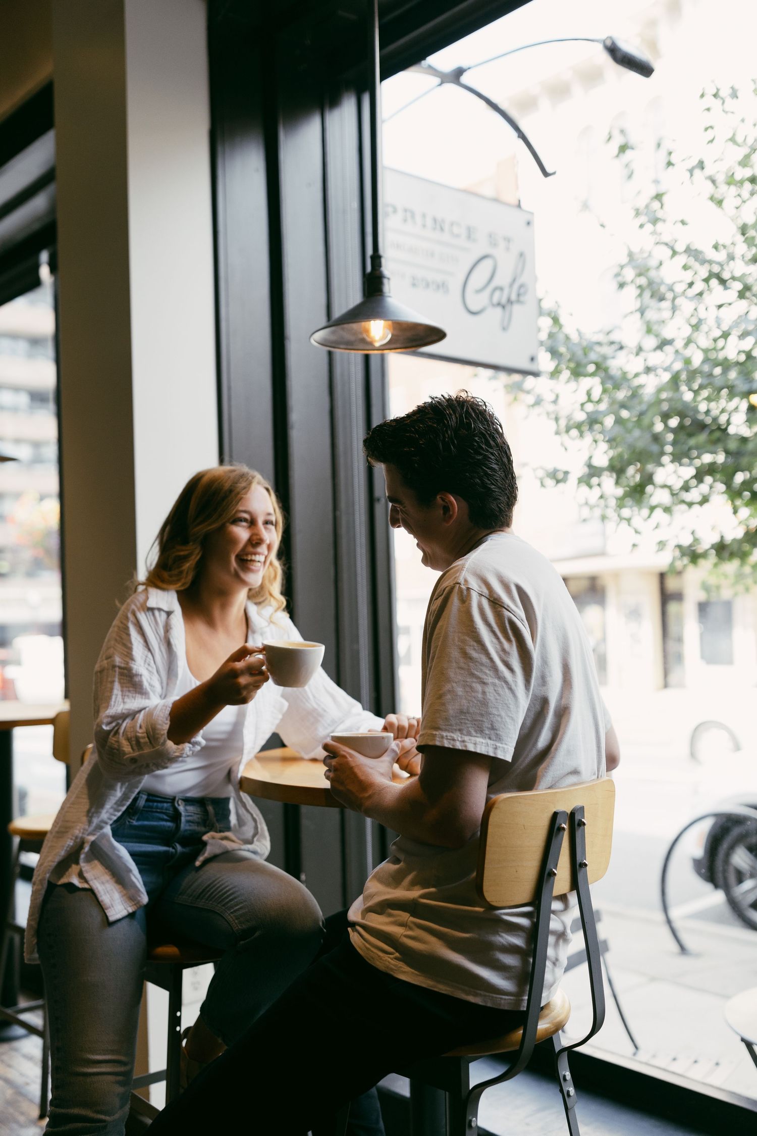 Couples enjoy coffee together at a modern cafe with large windows.