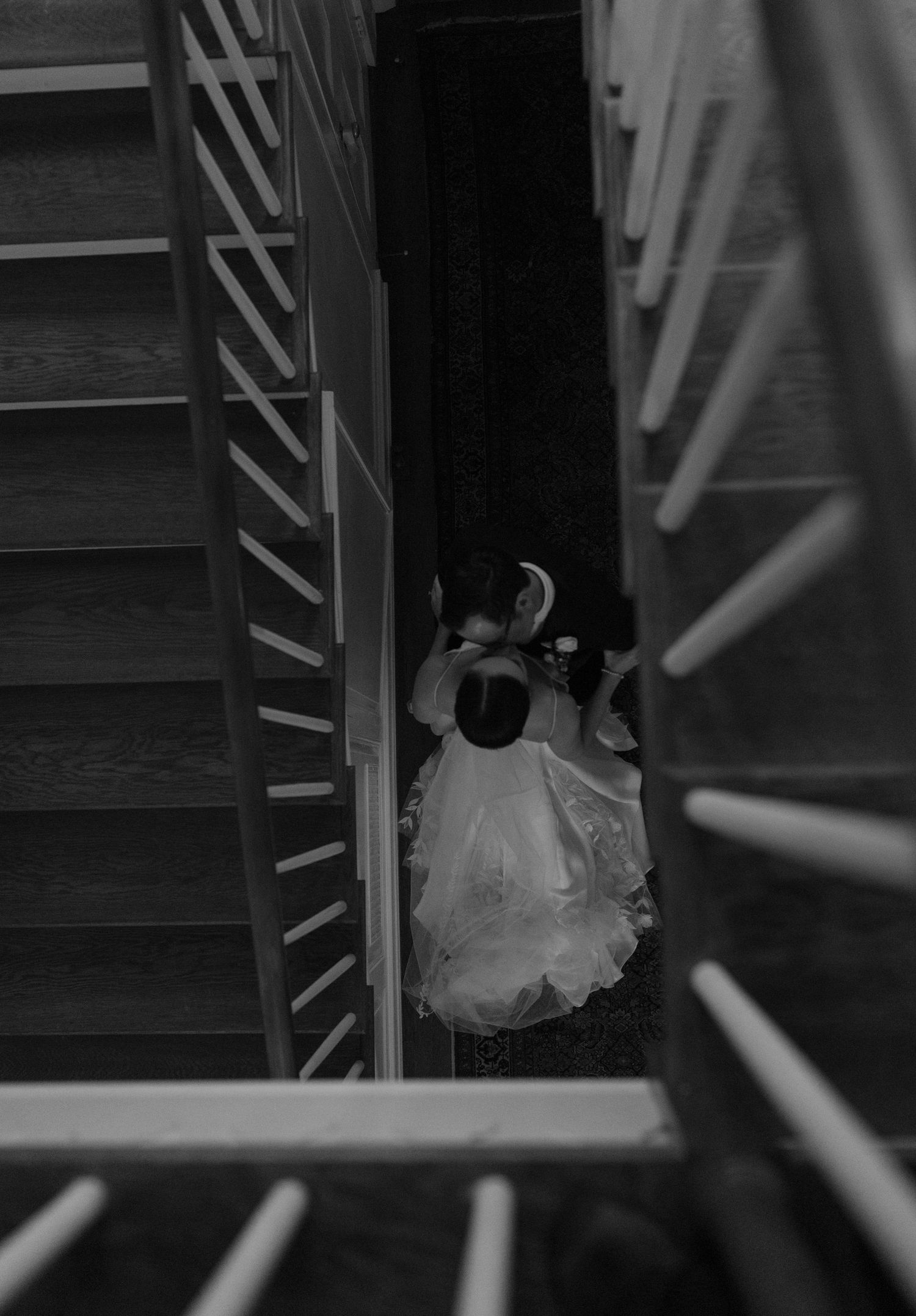 Artistic black and white staircase wedding photo sequence with flowing dress details.