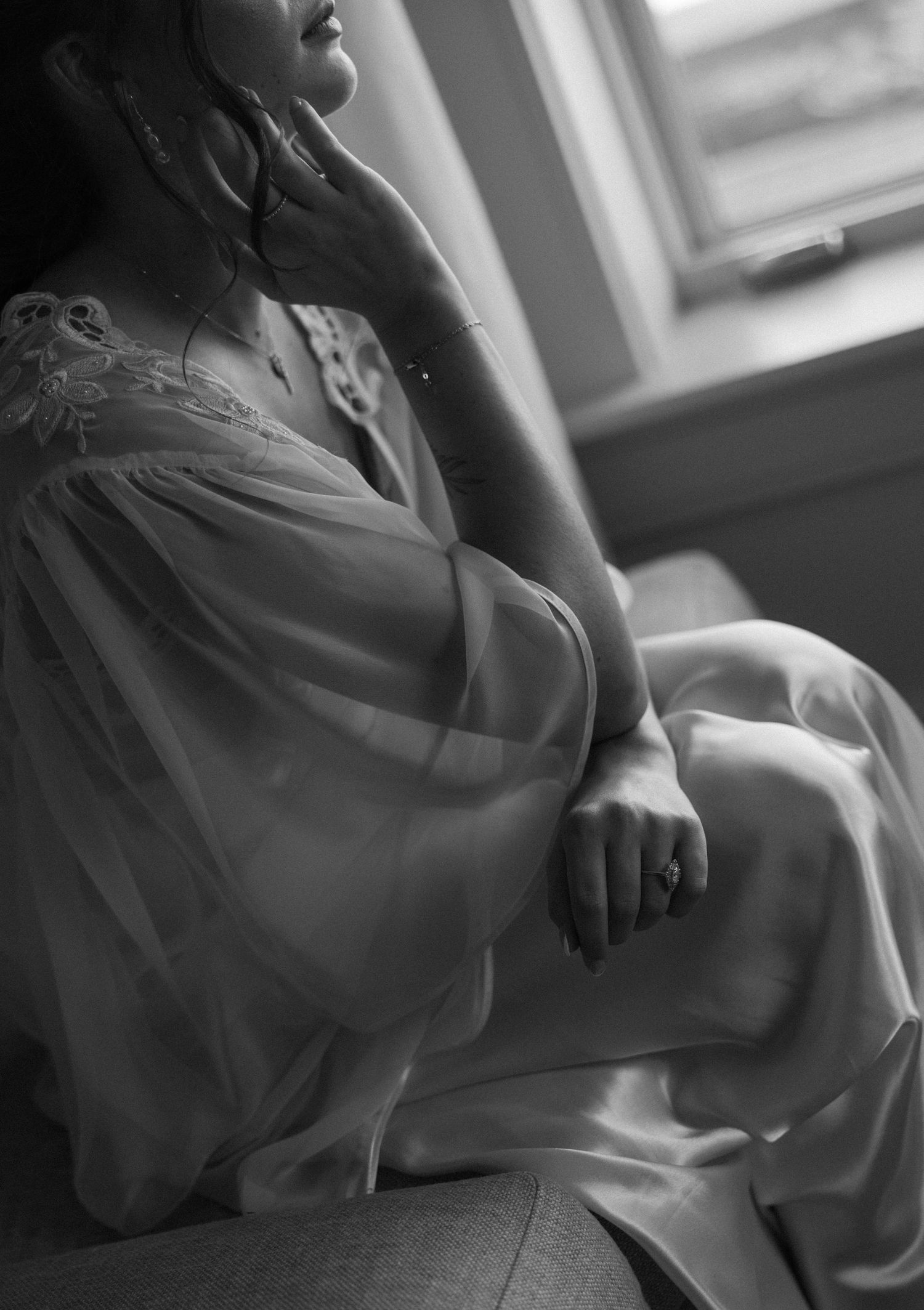 Intimate black and white boudoir photography session with soft window lighting.