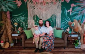 Family portrait setup with bohemian style backdrop and tropical greenery.