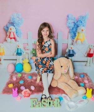 Easter photo setup with pastel pink backdrop, plush toys, and decorative spring elements.