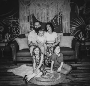 Black and white family photography session with macrame wall hanging and leather couch.