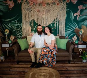 Professional family photo session with macrame backdrop and tropical decor elements.