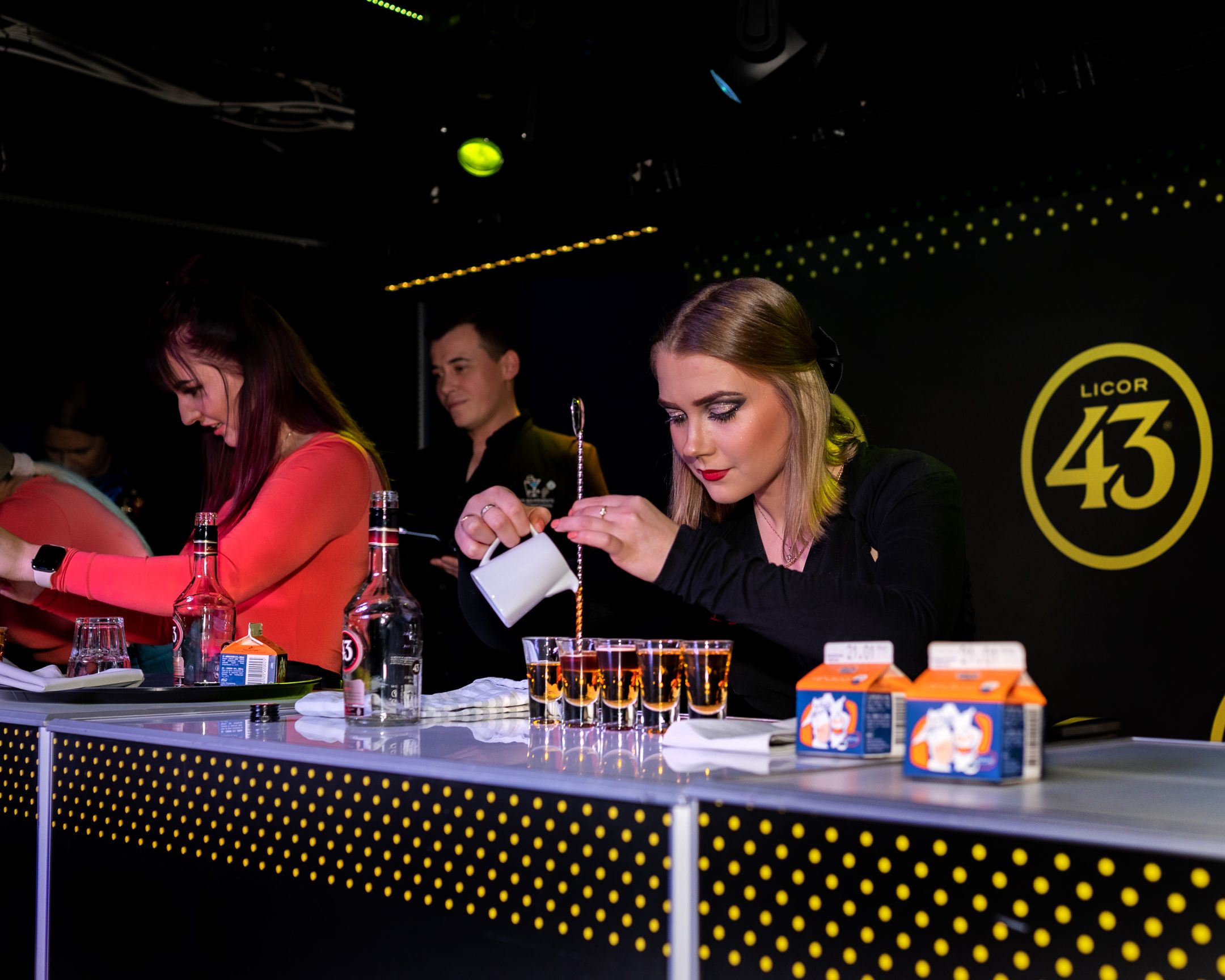 Professional bartenders making cocktails at a branded Licor 43 bar station.