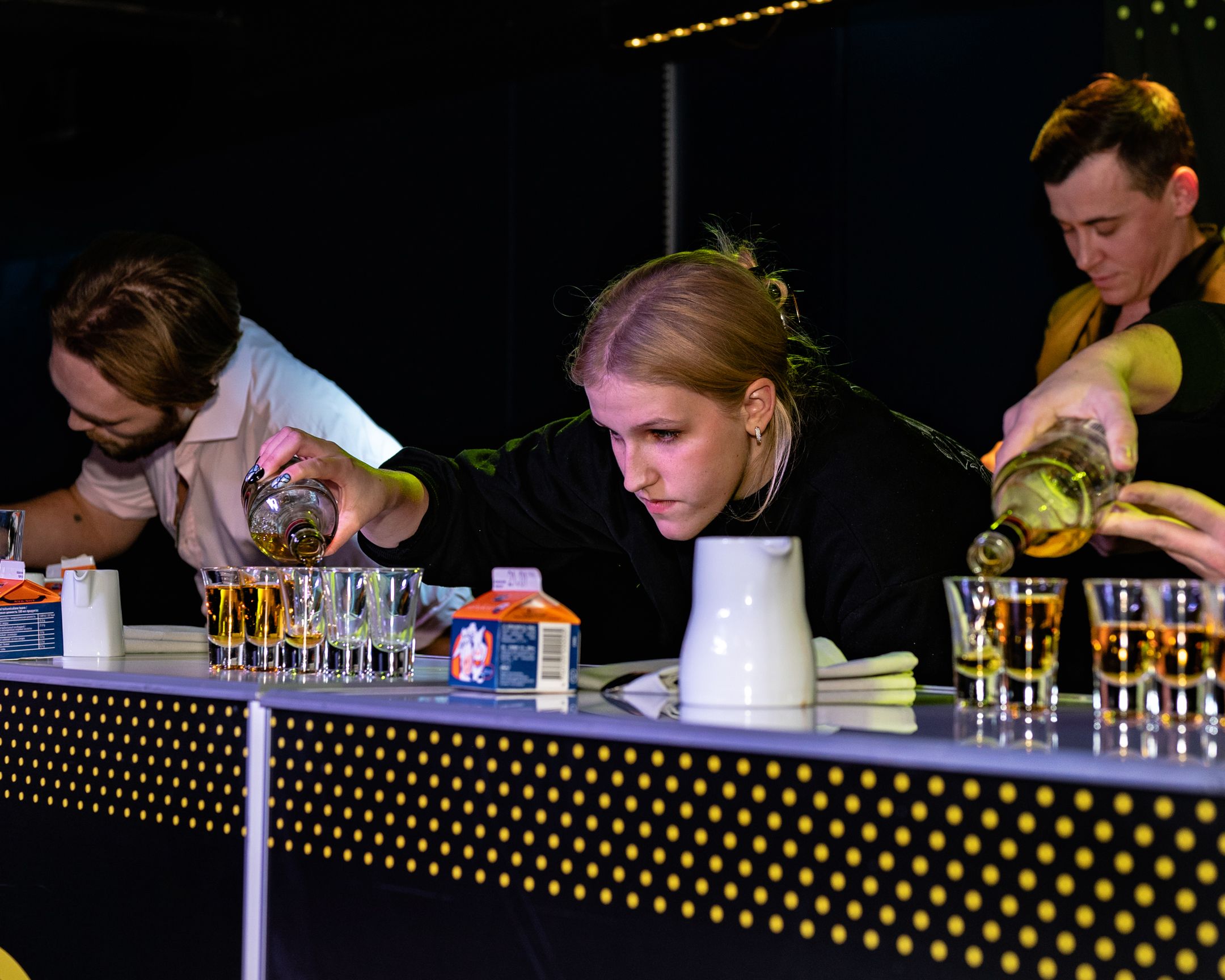 Three bartenders simultaneously pouring drinks at a dark venue with Licor 43 branding.