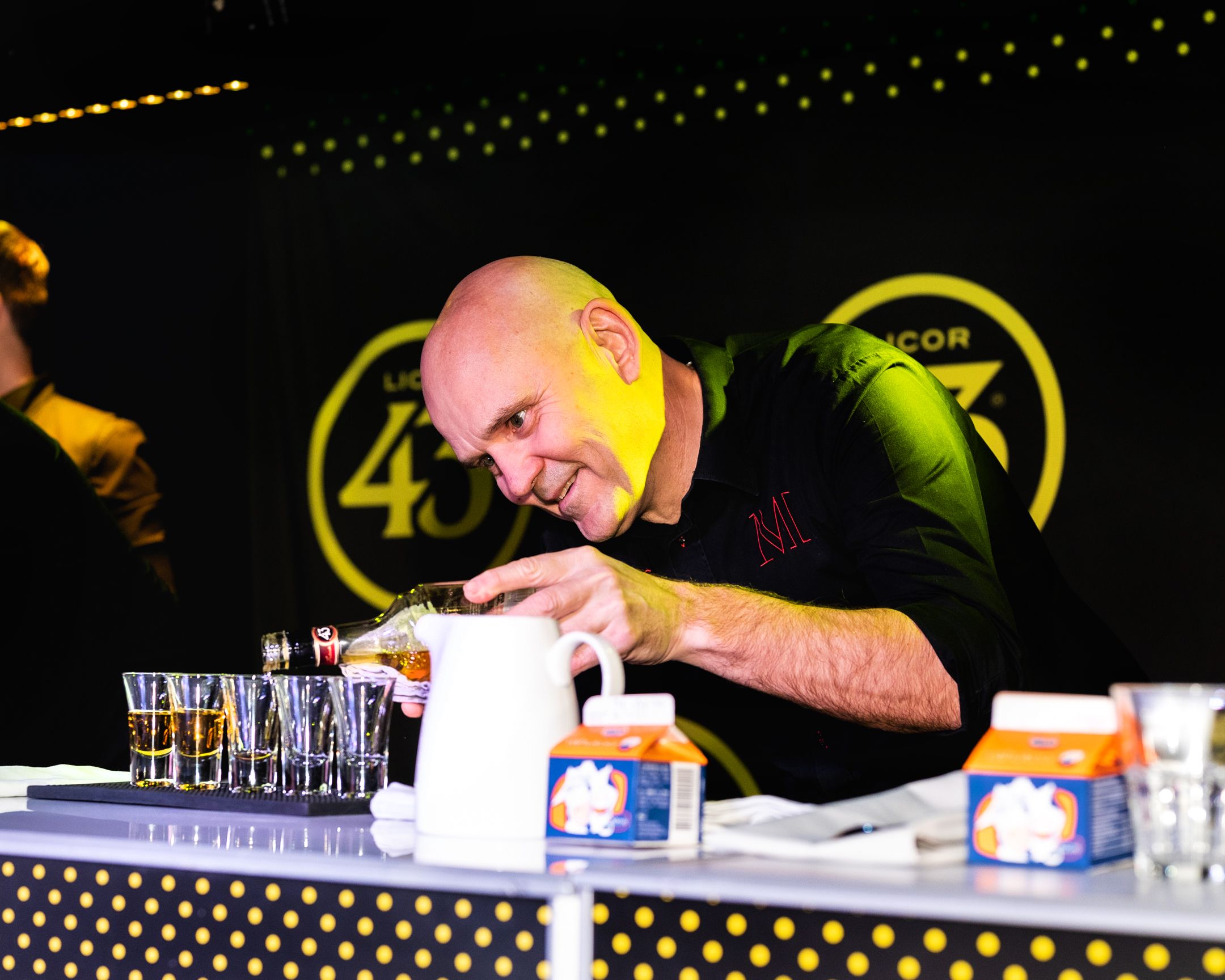 Bartender focused on precise pouring at an illuminated Licor 43 branded counter.