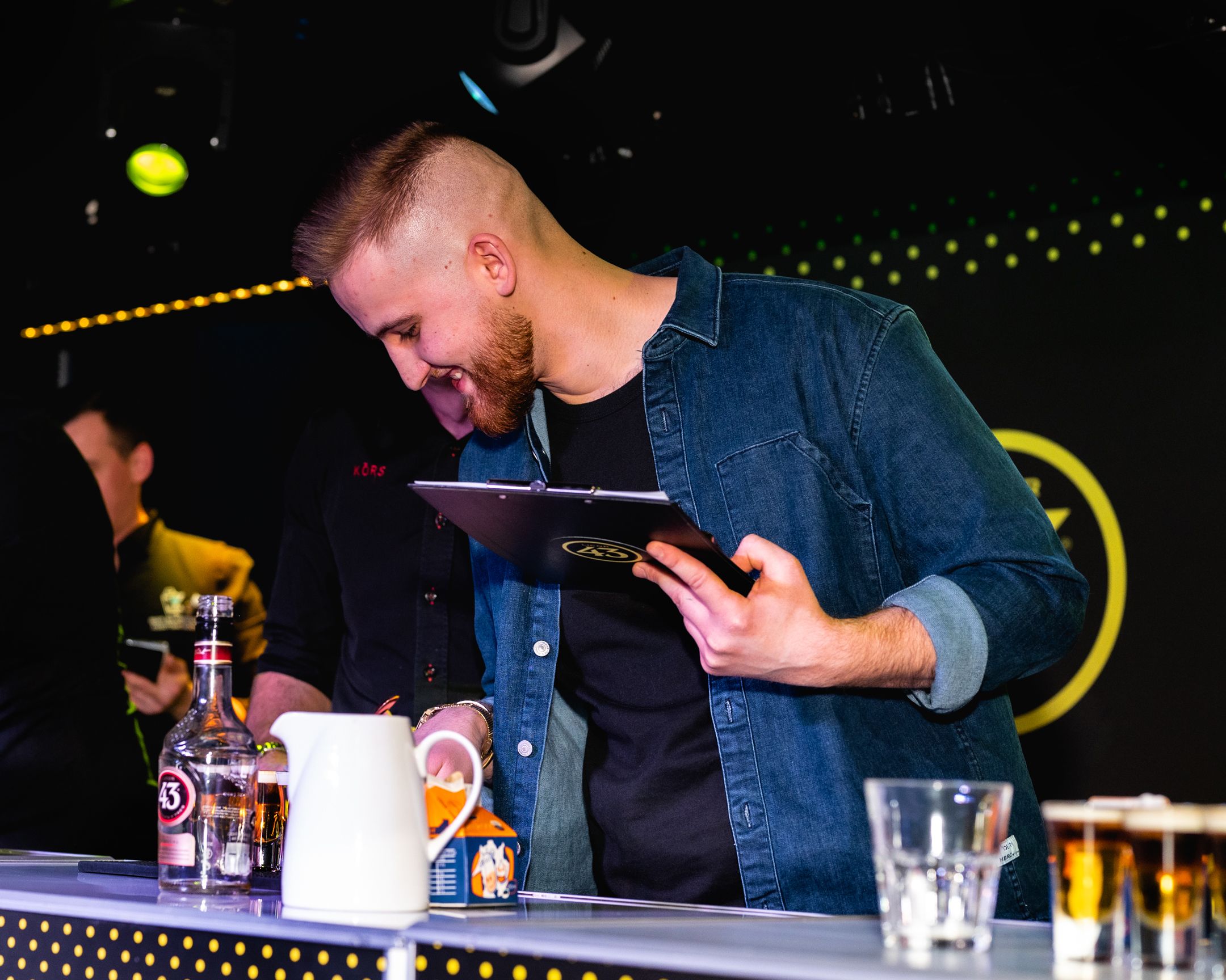 Enthusiastic bartender performing drink preparation at a Licor 43 promotional event.