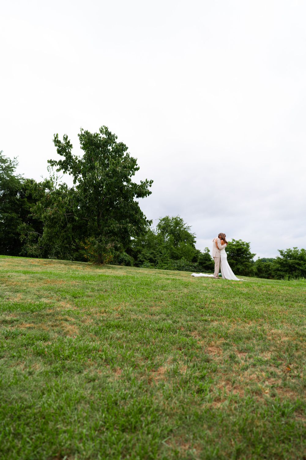 A scenic hilltop wedding portrait with rolling green hills in the background.