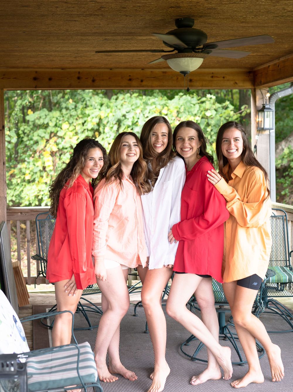 A group wearing colorful button-down shirts poses together on a covered porch.