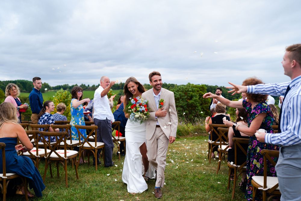 An outdoor wedding ceremony with wooden chairs and guests celebrating in a natural setting.
