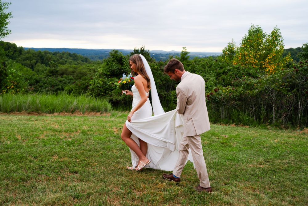 A couple walking through a hilltop meadow during their wedding photoshoot.