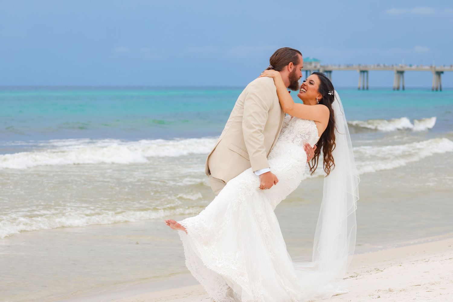 Romantic dip pose on beach with white dress flowing in ocean breeze.