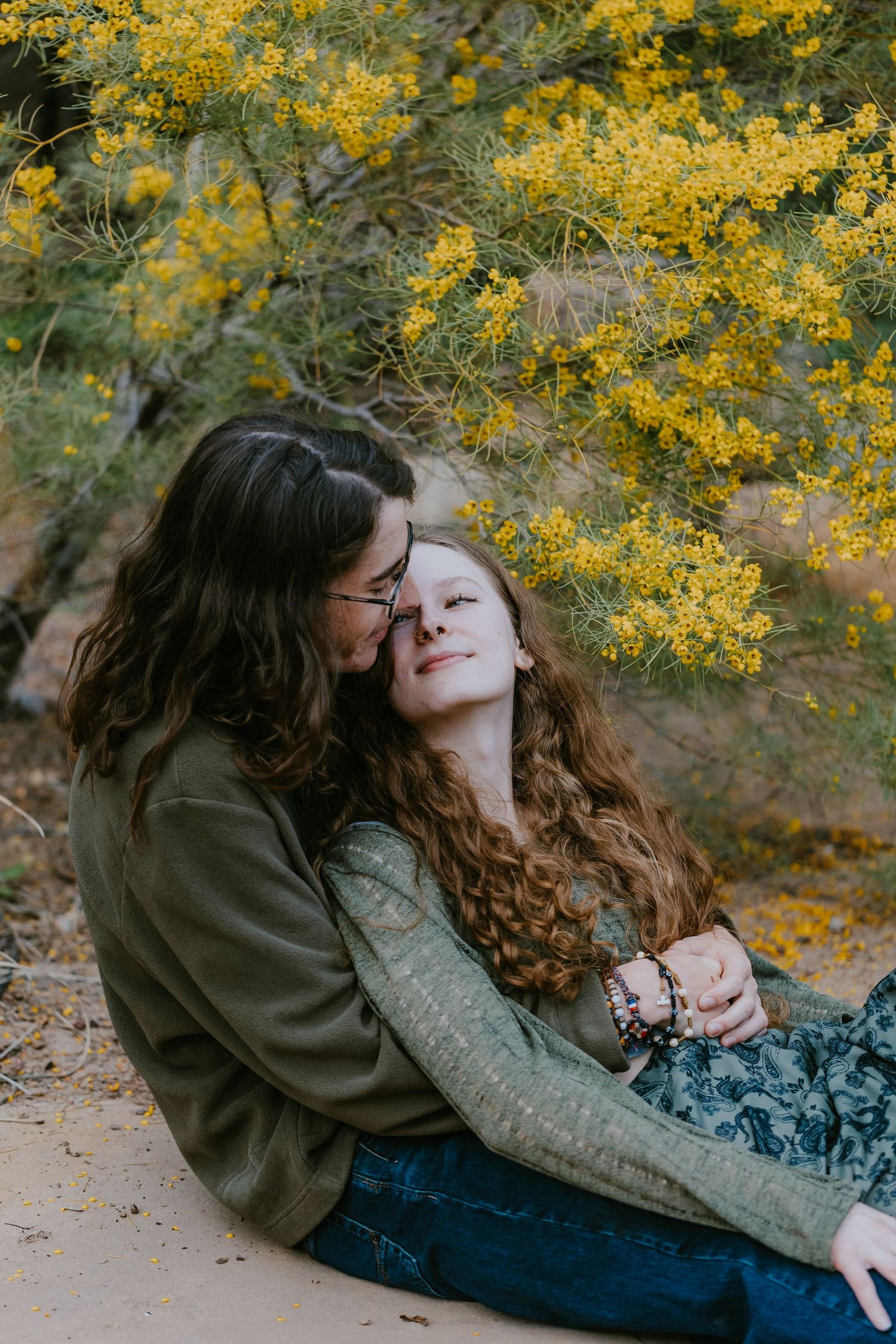 Romantic couple embracing under yellow flowering tree branches.