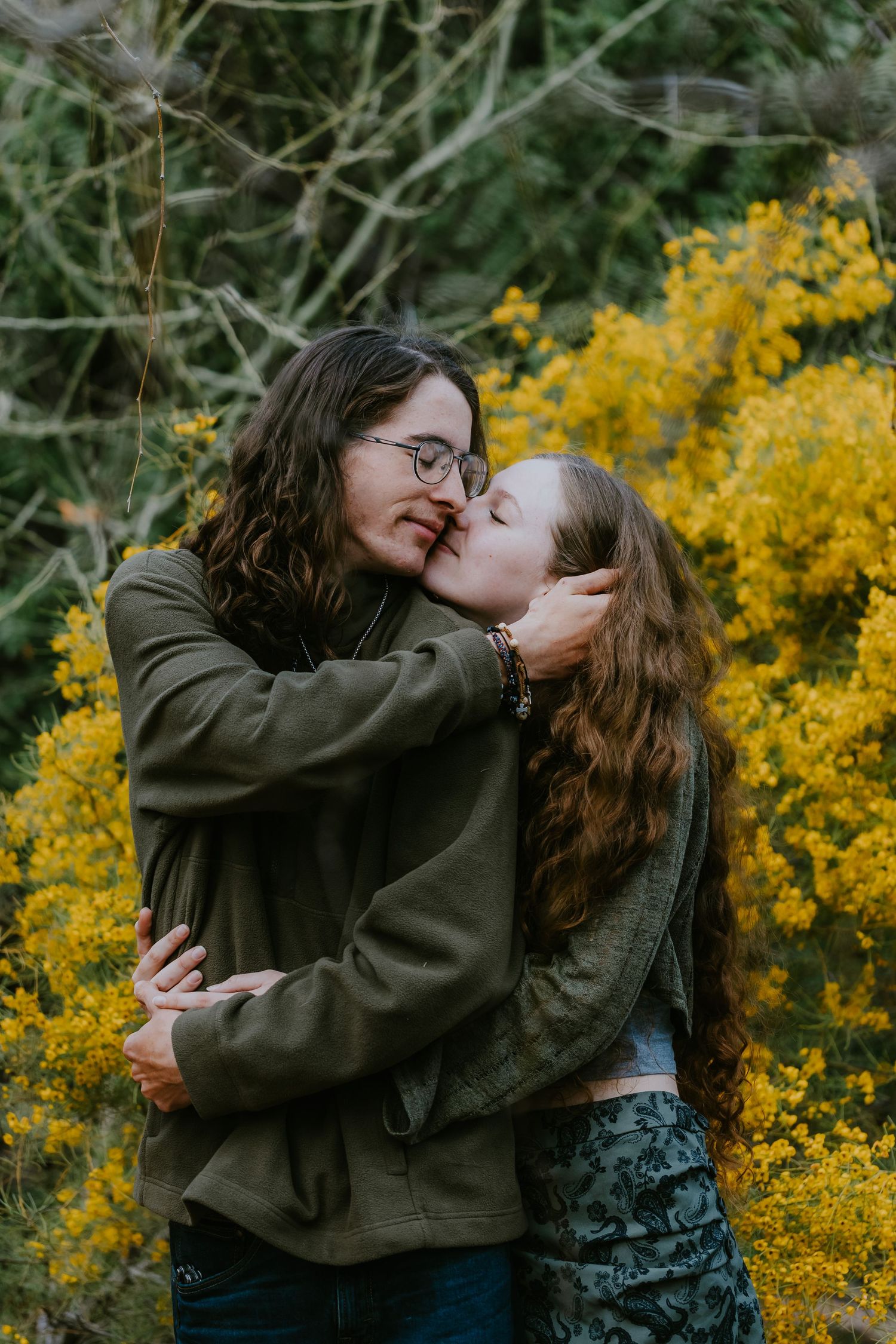 Intimate couple moment captured against backdrop of yellow spring flowers.