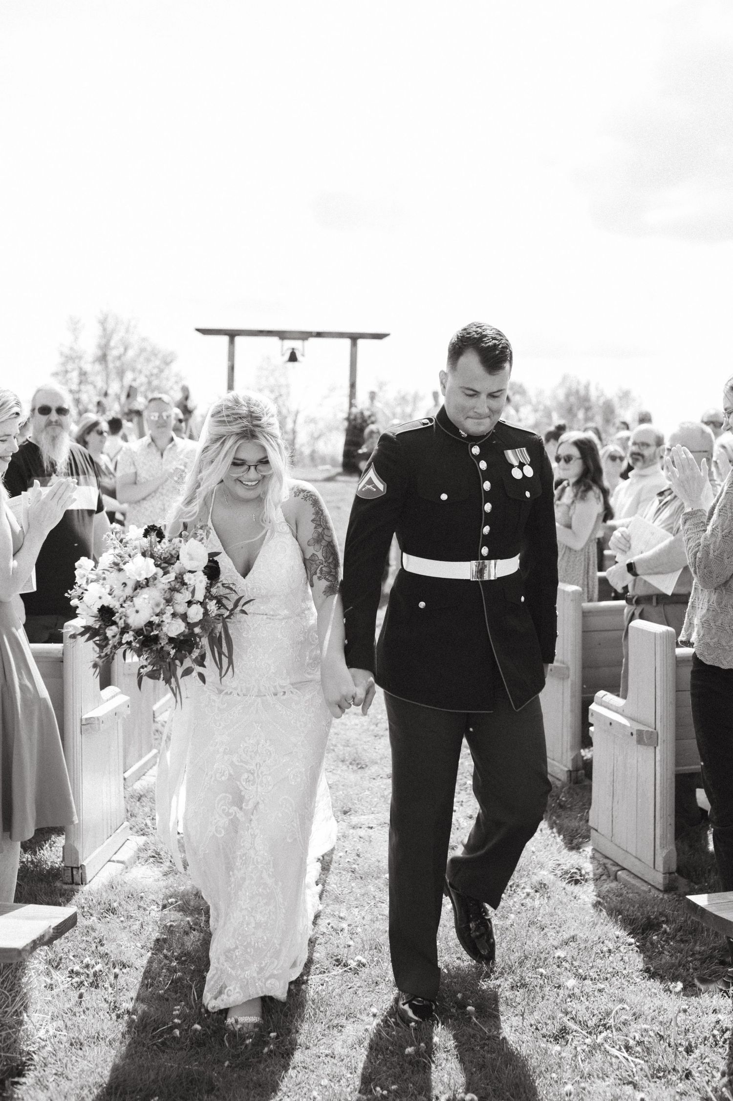 A military wedding ceremony exit with guests lining the aisle outdoors.