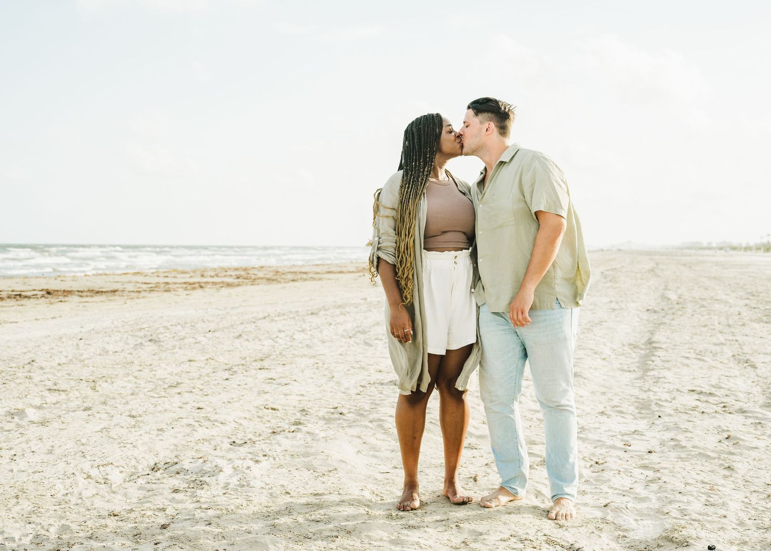 Couple walking together on pristine beach with gentle waves in background.