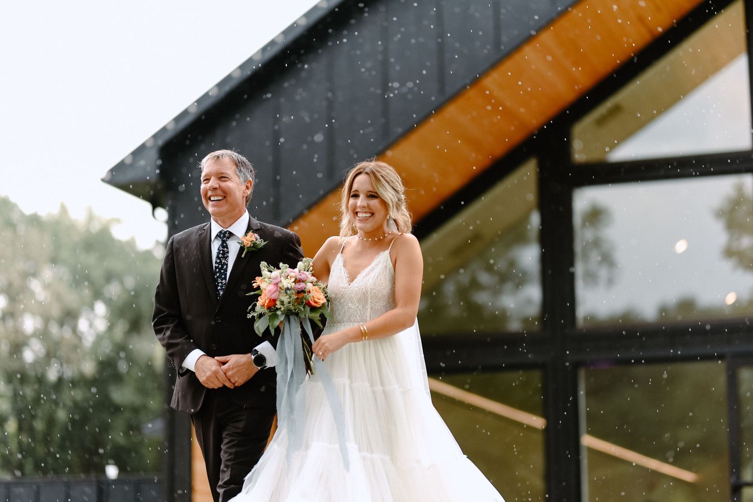 Rainy wedding photo outside modern black barn venue.