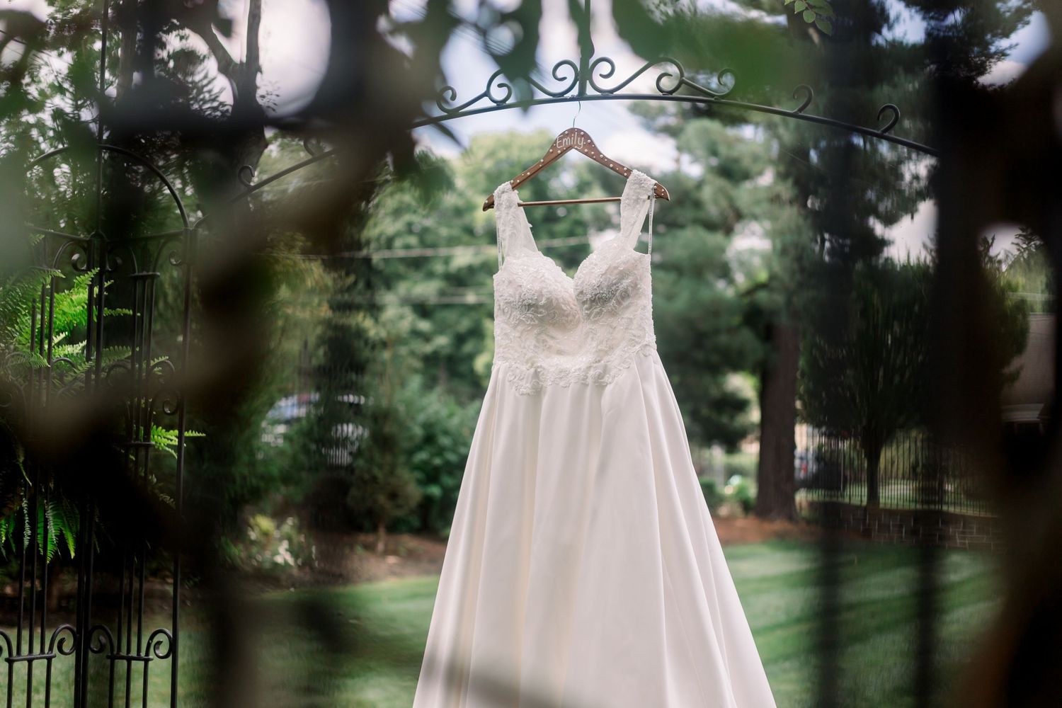 White wedding dress hanging outdoors against a natural garden background.