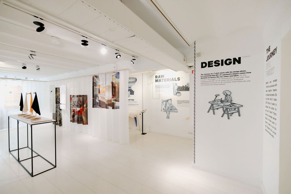 Clean gallery space with track lighting showcasing design exhibits and black metal display pedestals.