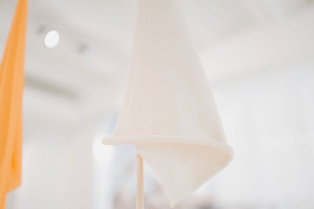 Abstract close-up of white and orange minimalist design elements in gallery setting.