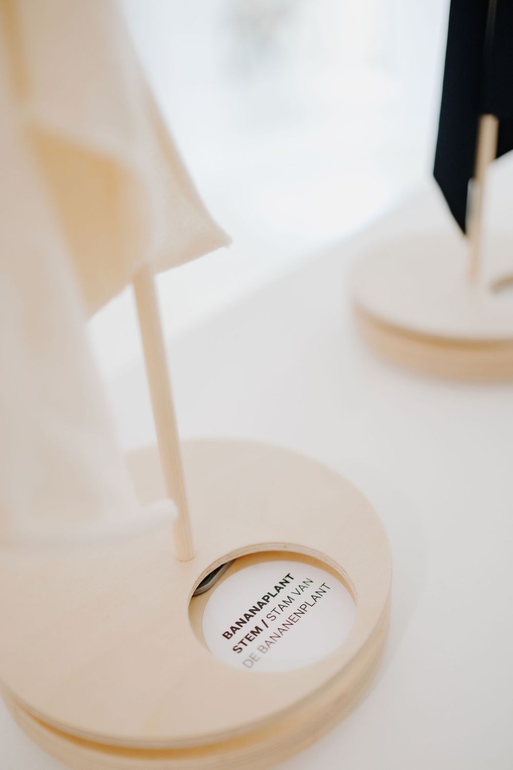 Close-up detail of white display stand with circular base and product label.