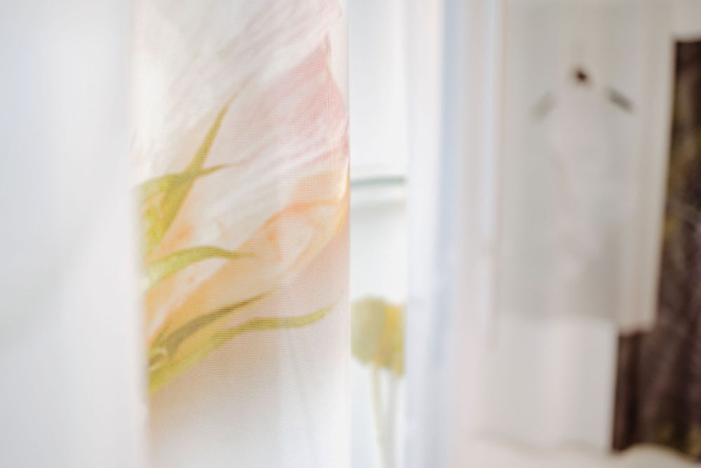 Soft focus view of translucent fabric with pastel yellow and pink watercolor-like patterns.