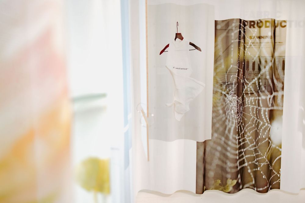 Gallery display featuring hanging garments and printed fabric with nature-inspired designs.