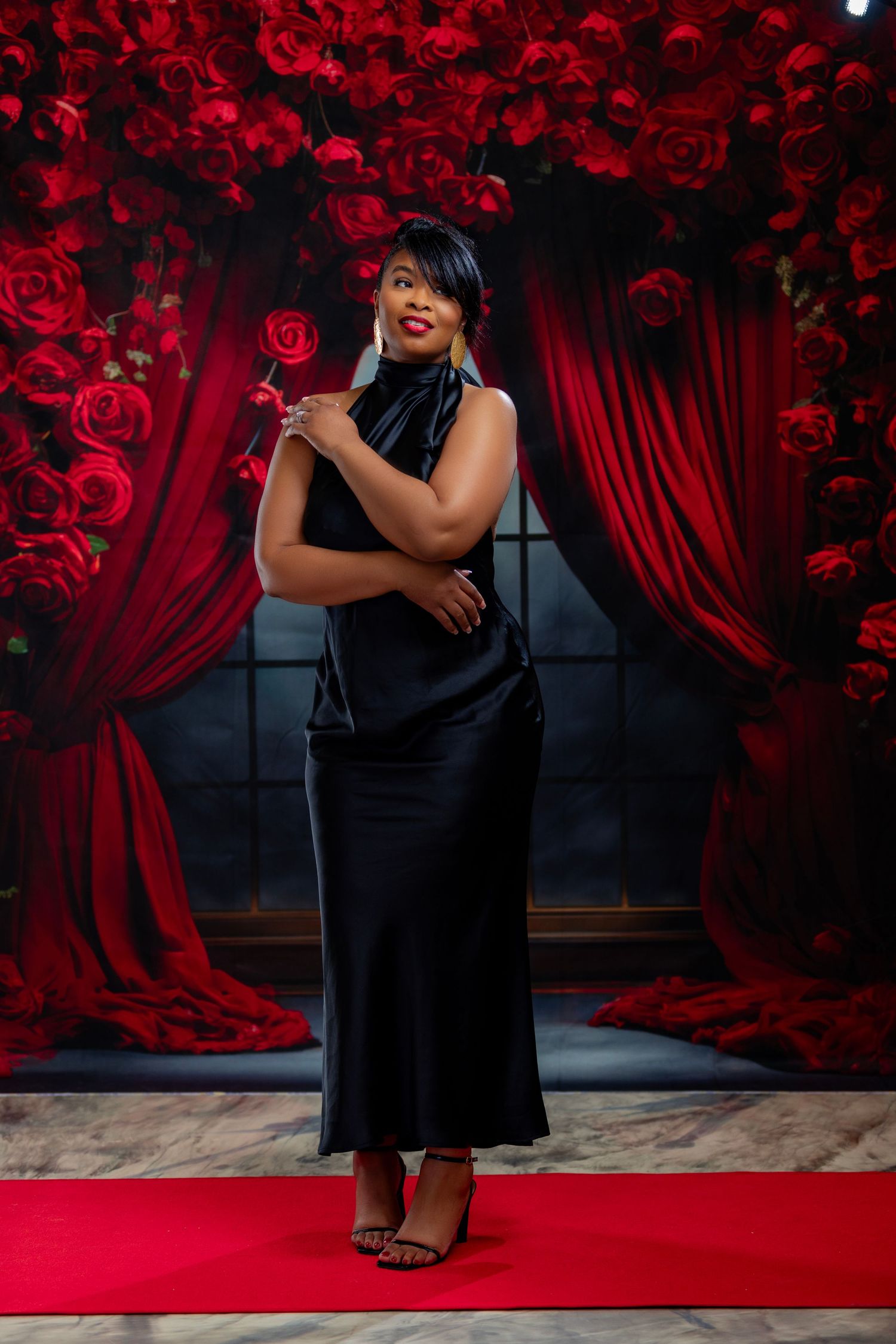 Against a stunning rose backdrop, our client gazes into the distance, enveloped in soft, moody lighting.