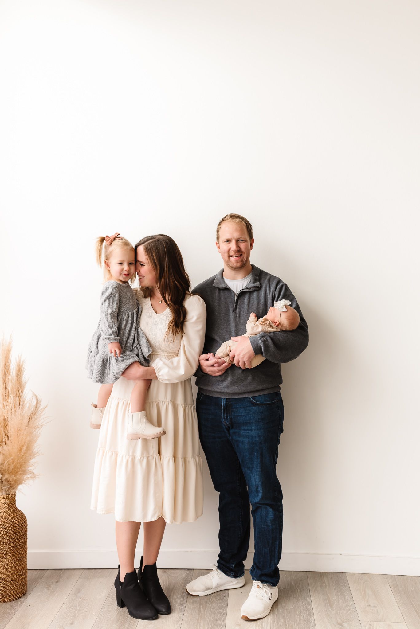 Family portrait session against white backdrop showing casual and playful interactions.