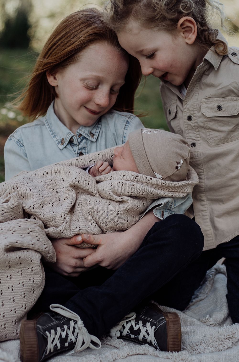 A tender moment of bonding while sitting on a blanket outdoors together.