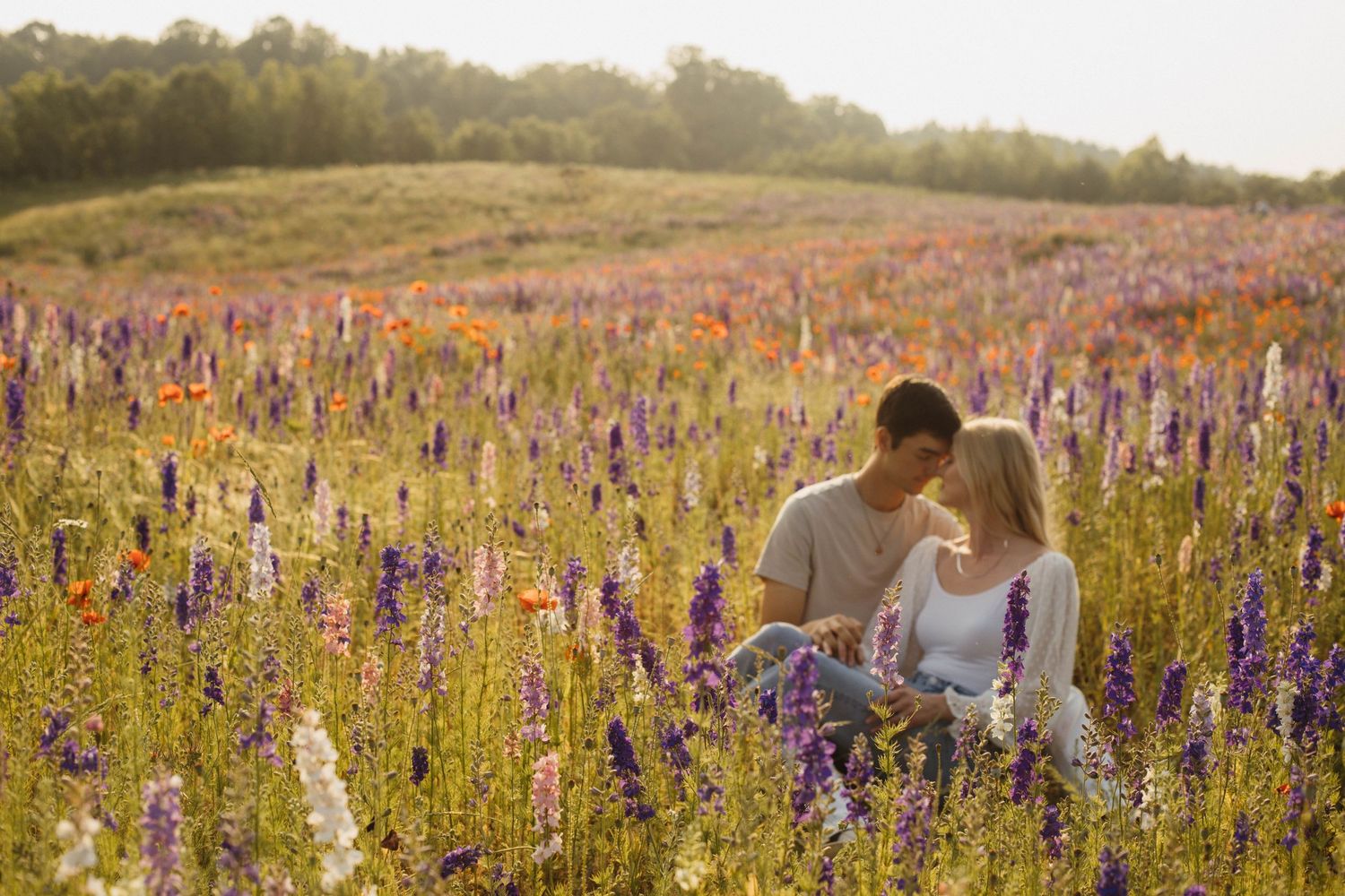 Romantic couple embraces in a blooming wildflower meadow at sunset with purple and yellow flowers.
