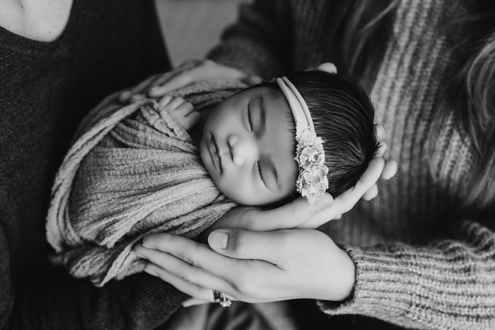 Baby sleeping peacefully on soft knitted blanket in natural light.