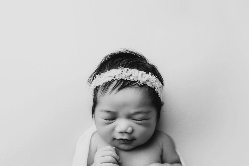 Monochrome close-up of sleeping infant with lace headband.