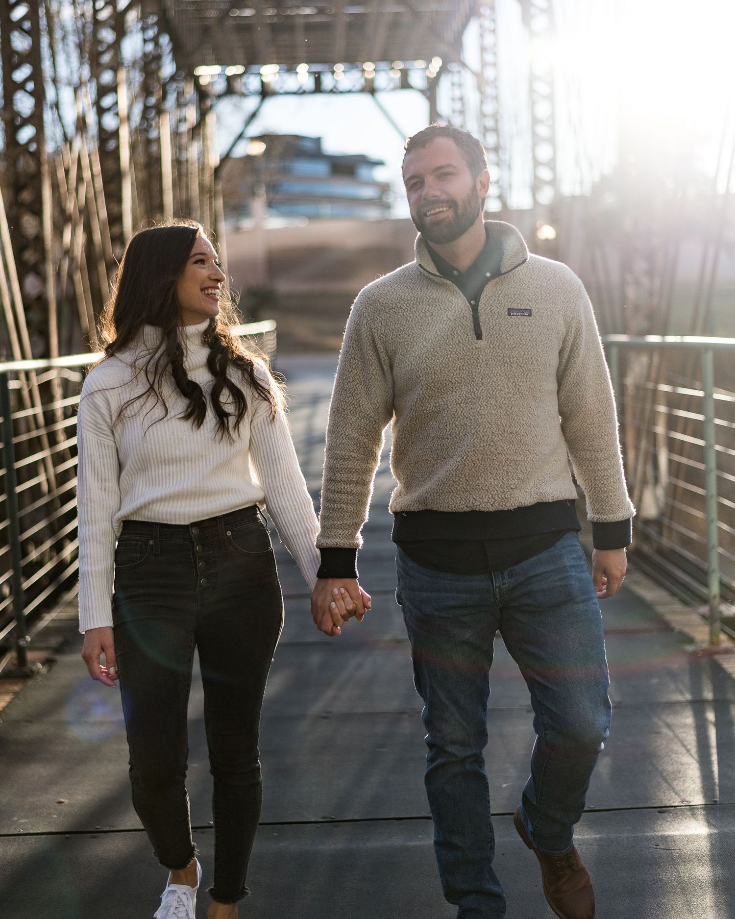 A couple walking together on a boardwalk during golden hour sunset.