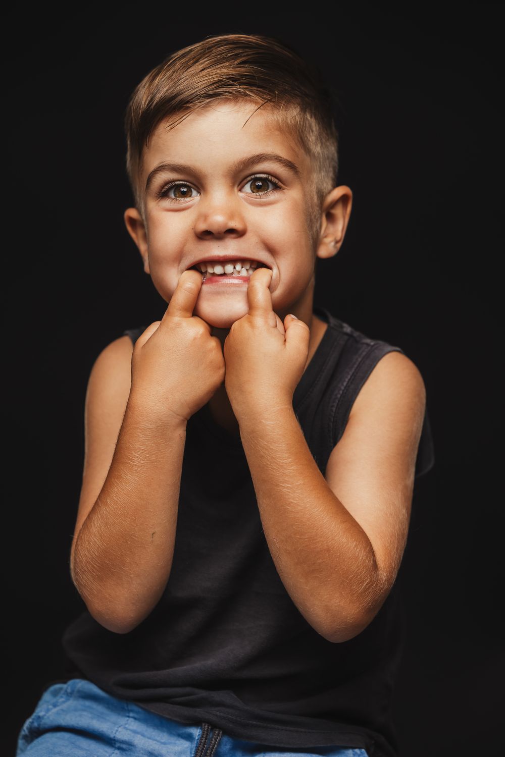 Close-up sequence of young child making playful expressions against dark background.