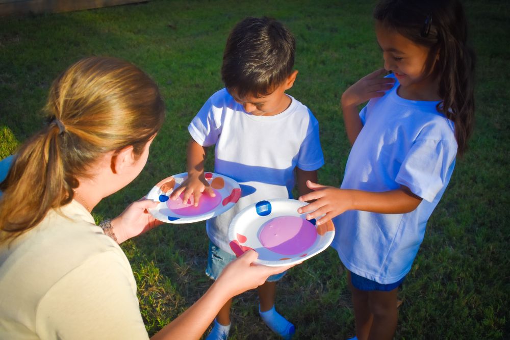 Children sharing colorful plates during an outdoor activity.