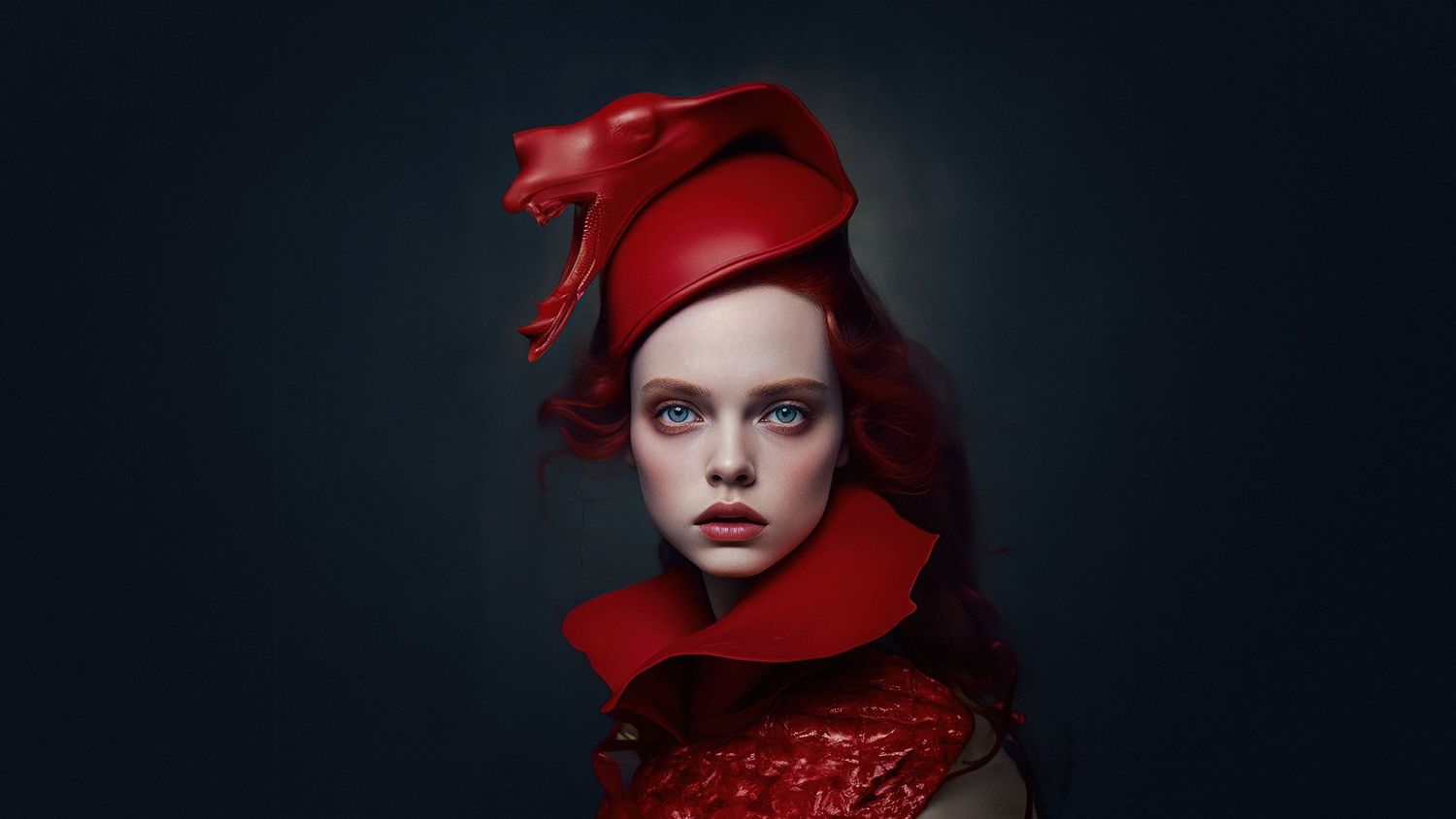 Dramatic portrait in red clothing and matching hair against dark backdrop.