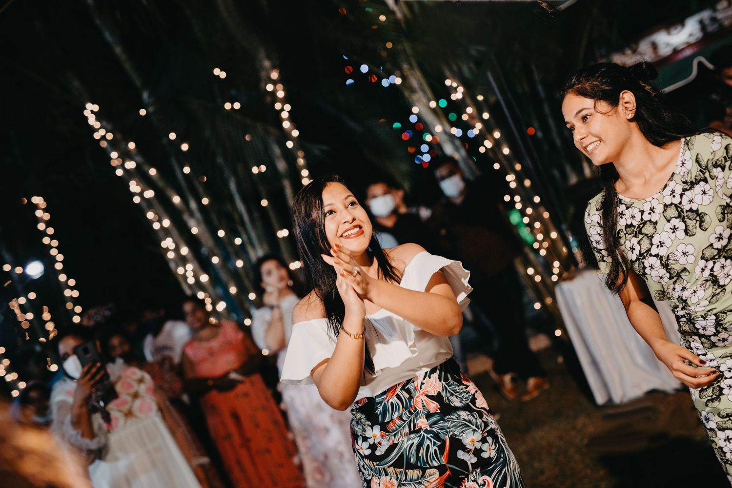Evening party scene with string lights and dancing silhouettes.
